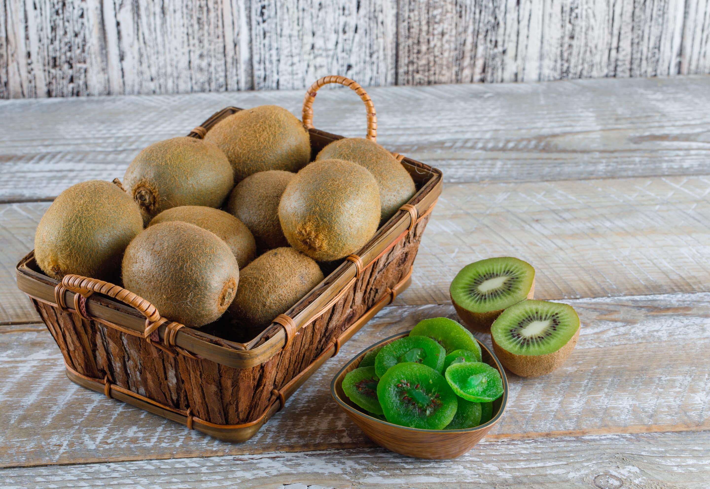 kiwi in a basket with dried slices high angle view on a wooden background